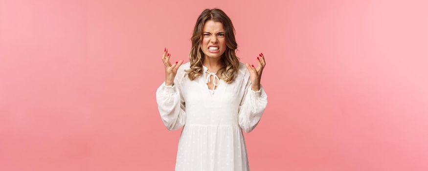 Portrait of woman losing control over emotions, feel pressured and tensed, lose temper, clench hands into fists and stare aggressive with angry, outraged expression, hate someone badly.