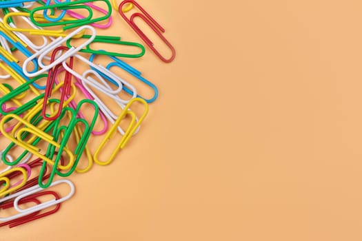 Multicolored Paperclips Isolated on a Cheerful Orange Beige Background with Copy Space on Right. High quality photo