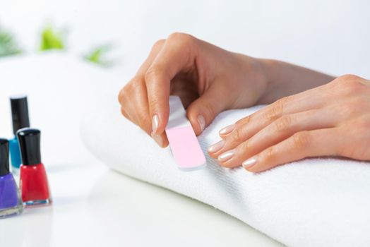 Woman hand using nail file and create perfect nails shape. Closeup grinding female nails with nail file. Woman doing herself nail care procedure at home. Natural beauty and hygiene concept