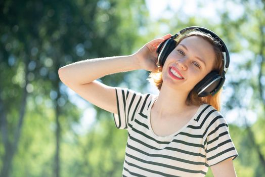 Young attractive woman listens to music in the park. Enjoying music in the park