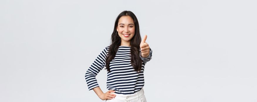 Lifestyle, beauty and fashion, people emotions concept. Cheerful cute asian girl thumb-up in approval, wink encouraging and smiling, praising nice job, say well played as congratulate with win.