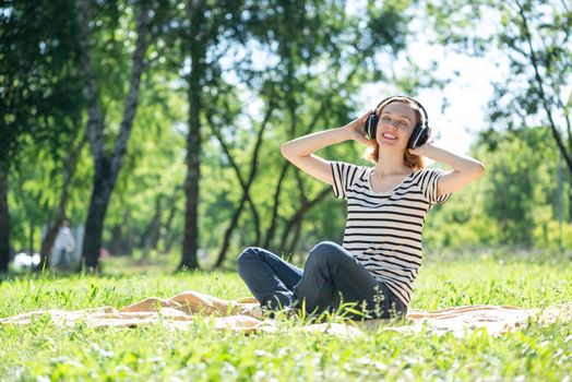 Young attractive woman listens to music in the park. Enjoying music in the park