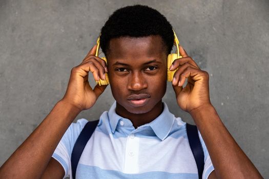 Teenage African American boy looking at camera holding headphones with hands. Lifestyle concept.