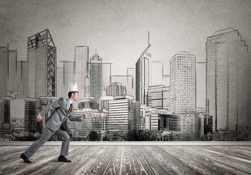 Young handsome businessman wearing white paper crown running in a hurry