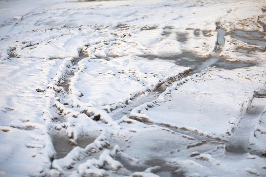 A country road full of car ruts covered with fresh snow. Winter aura on dirt roads outside the city.