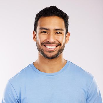 Studio shot of a handsome and happy young man posing against a grey background.