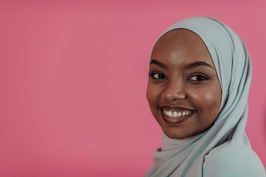 Portrait of young modern muslim afro beauty wearing traditional islamic clothes on plastic pink background. Selective focus. High quality photo