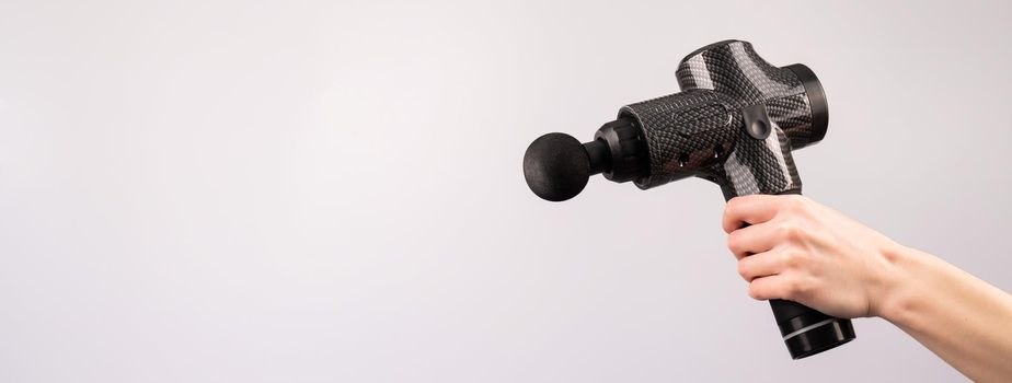 Close-up of a female hand with a portable massager gun on a white background