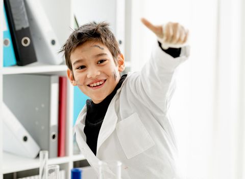 School boy showing super with hands holding big fingers up during chemistry experiment in elementary science class. Clever pupil kid in lab