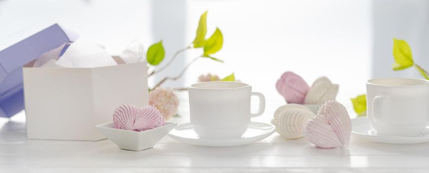 Heart shape marshmallows pink and white color and cups with tea. Craft desert sweets with beverage romantic composition for Valentine day