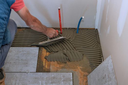 A man worker puts the tile using adhesive cement