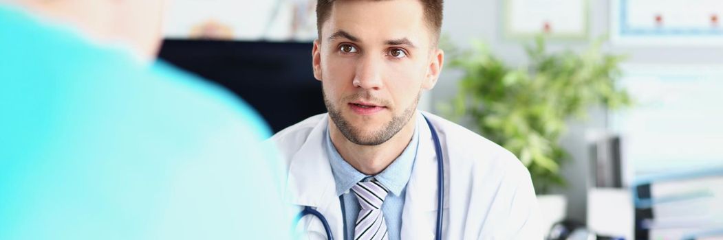 Portrait of young male doctor in uniform and stethoscope, work meeting in head doctor office. Listen to instructions of professional specialist, plan for work. Hospital, medicine concept