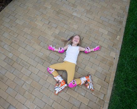 Little girl learns to roller skate and falls. View from above.