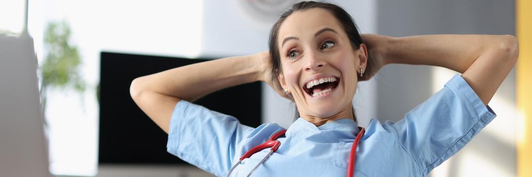 Portrait of laughing medical worker on break, doctor watch video on laptop, free time, qualified female in office. Medicine, healthcare, clinic, lunch, spare time, fun concept