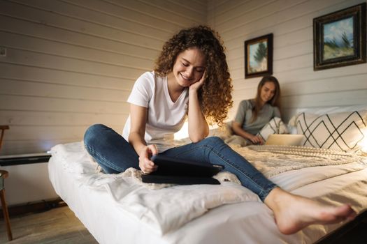 Two beautiful women lying in bed, holding and watching laptop