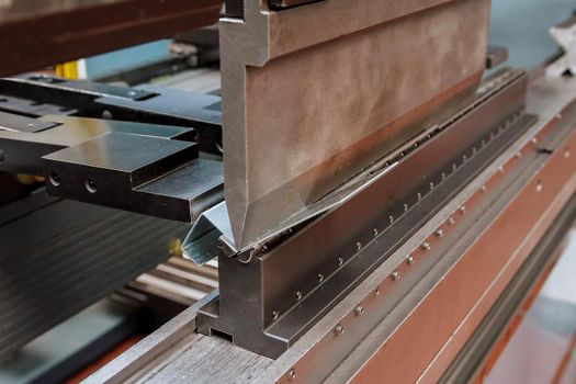 The process of bending galvanized sheet metal 2 millimeters thick on a special machine for bending metal plates.