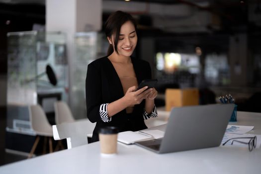 Business asian woman using mobile phone during checking an email or social media on internet. accounting financial concept