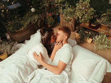 loving married couple lie on bed in hotel, relax together. man and woman in bathrobes have rest, leisure time, enjoy. look at each other with love