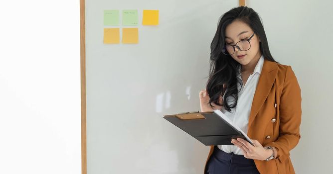Young asian business woman entrepreneur looking at financial report in the office.