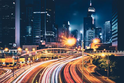 Street traffic in Hong Kong at night. Office skyscraper buildings and busy traffic on highway road with blurred cars light trails. Hong Kong, China