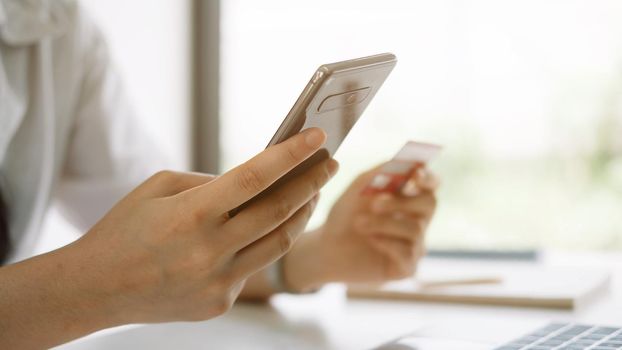 Shopping online with smartphone and credit card on hand.