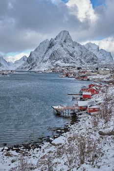 Reine fishing village on Lofoten islands with red rorbu houses in winter with snow. Norway