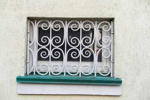 Forged lattice with pattern on closed window of an antique red brick rear