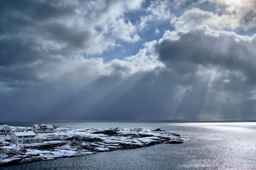 Norwegian sea in winter with sun rays through clouds. Lofoten islands, Norway