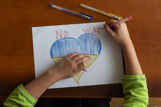 Ukrainian flag and a heart in yellow and blue color. Child draws a heart on the blackboard.