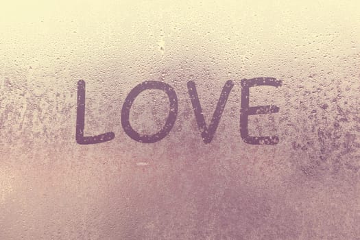 Word Love and shape of heart are drawn with a finger on fogged window glass. Valentine's Day, Valentine card creative. Blur Love sign drawing, blurred background. February its month love, concept