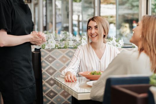 Two Happy and Cheerful Women Having Lunch Time, Making Order to Female Waiter in Restaurant