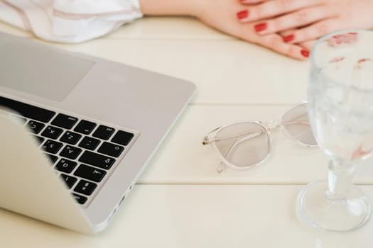 Close Up of Unrecognisable Woman Sitting by Table with Laptop, Glass of Water and Glasses, Freelance Concept