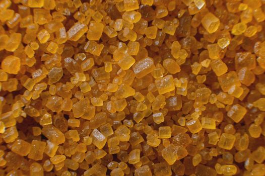Extreme macro. Sugar crystals. Close-up of brown cane sugar on a plane. Texture or background of wholesome brown sugar.