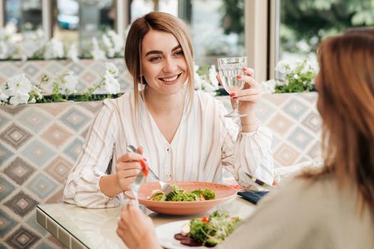 Cheerful Young Woman Having Lunch with Her Female Friend in Restaurant