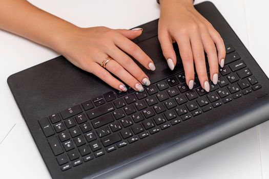 European professional woman sitting with laptop at home office desk, positive woman studying while working on PC. She is wearing a red plaid shirt and jeans