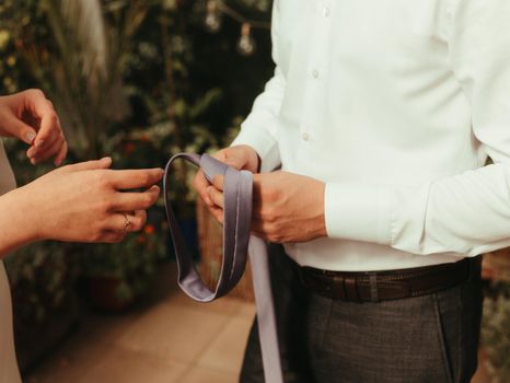 bride helps groom to wear a tie grain effect blond