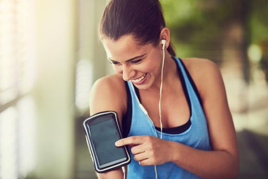 Shot of a young woman starting her playlist before working out.