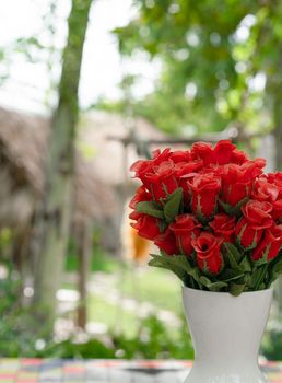 Fake red roses flowers in vase on table