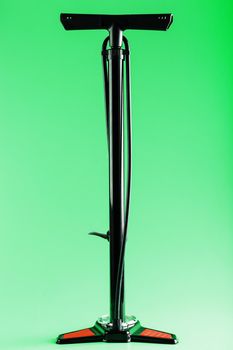 Black bicycle manual air pump for pumping wheels on a green background with a vertical composition