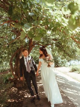 Happy wedding couple walking in a botanical park grain effect