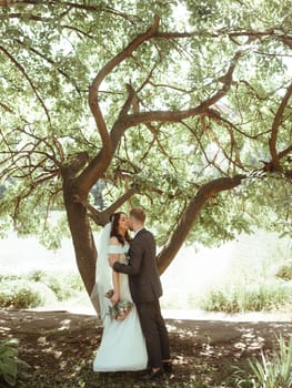 Happy wedding couple walking in a botanical park grain effect