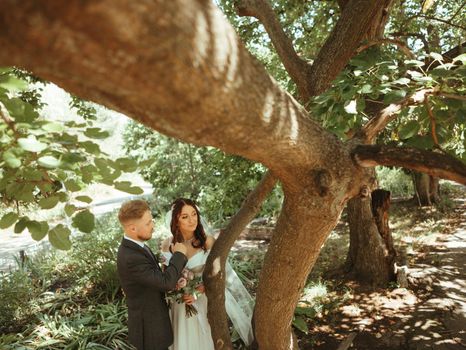 Happy wedding couple walking in a botanical park grain effect