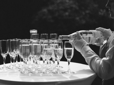 pouring champagne for a toast in a celebratory atmosphere with glasses of champagne on golden bokeh grain effect