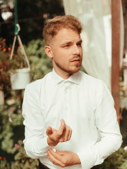 Portrait of a happy young husband in a wedding tuxedo standing on a pier in the middle of a forest lake. Concept for a classic European outdoor wedding