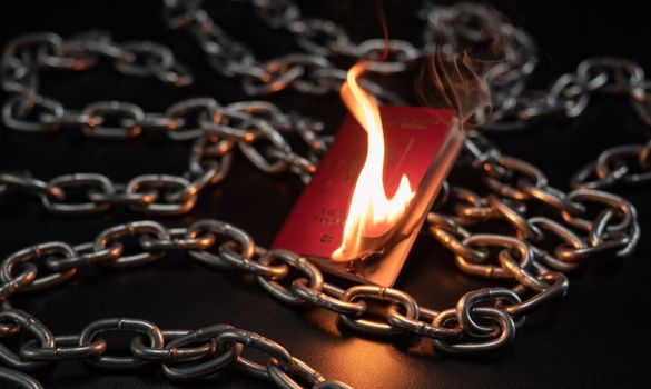 the Russian passport is on fire against the background of a metal chain