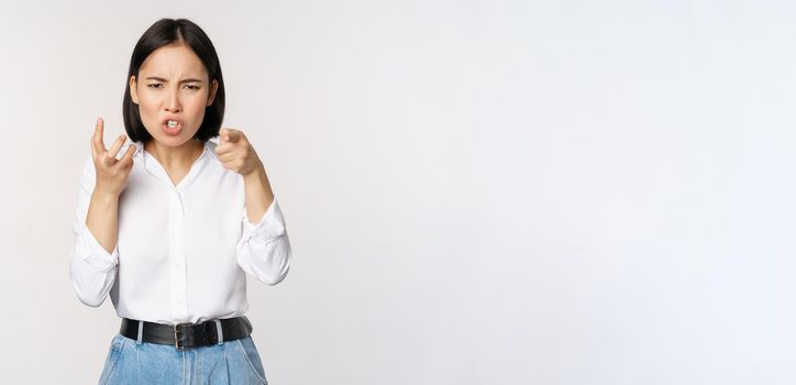 Image of angry pissed off woman shaking from anger, clench hands and grimacing furious, annoyed and outrated, standing over white background.