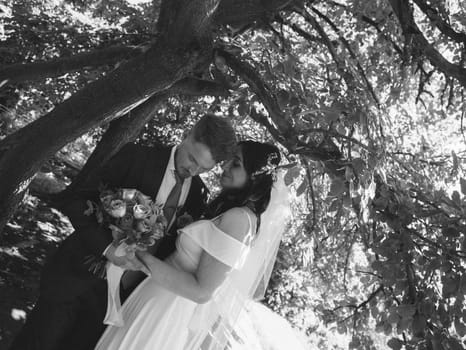 Happy wedding couple walking in a botanical park grain effect