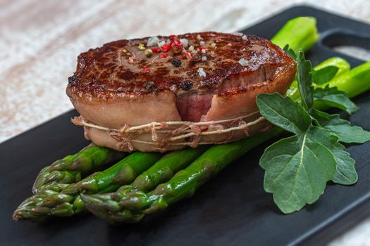 Close-up of a bleeding tournedos on a bed of green asparagus and fennel