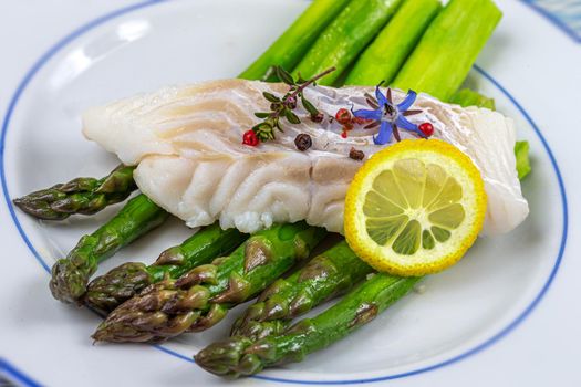 Cod pavement placed on green asparagus, seen from above.