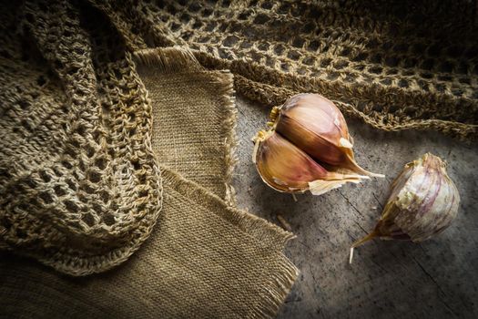 Garlic cloves and natural linen napkin on rustic wooden background